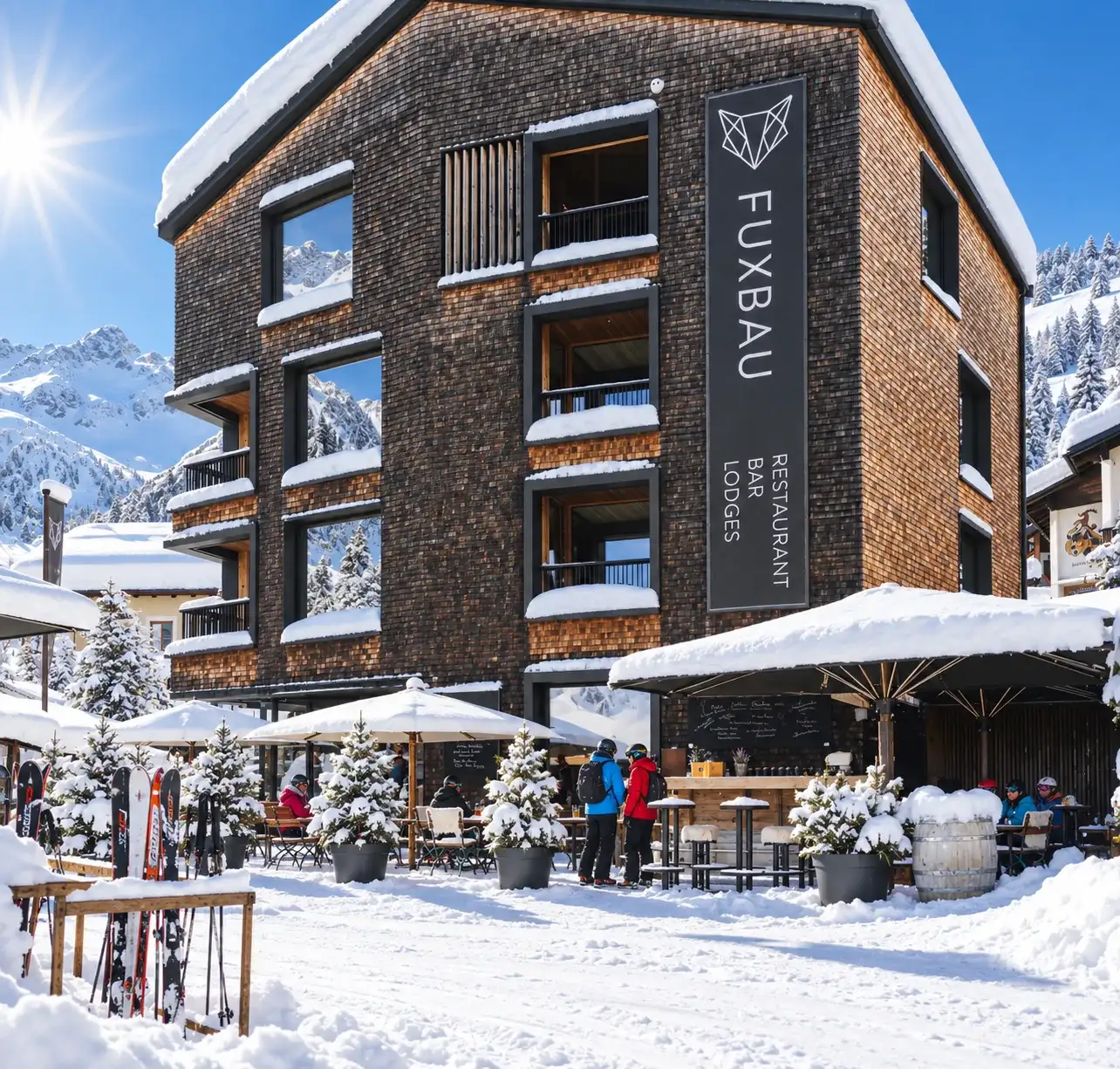 Après-Ski und Winteraktivitäten in Stuben am Arlberg Der Fuxbau in Stuben am Arlberg mit Schirmbar und abgestellten Ski an einem Wintertag
