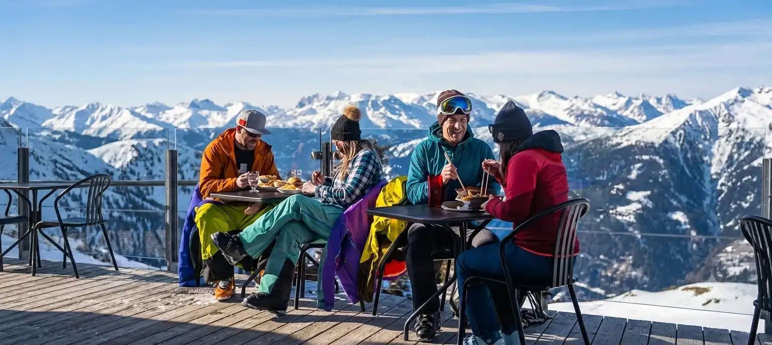 Four skiers stopping for lunch on a sunny mountain terrace above St. Anton am Arlberg
